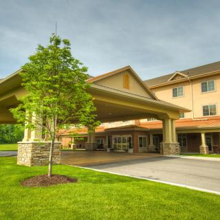 A hotel's exterior entrance with a covered driveway and surrounding greenery.