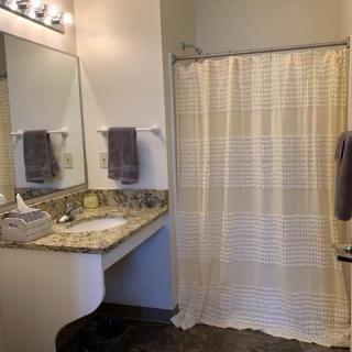 A bathroom featuring a large mirror, countertop sink, and a shower with a striped curtain.