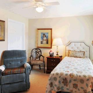 A cozy bedroom with a single bed, chair, and decorative artwork.