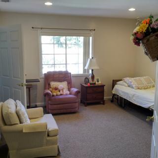 A cozy bedroom with a single bed, armchair, and a window allowing natural light in.