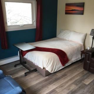 A cozy bedroom with a neatly made bed, a side table, and a window providing natural light.