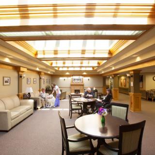 A well-lit lounge area with a skylight, comfortable seating, and people gathered around tables.