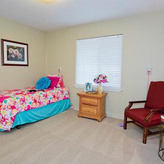 A cozy bedroom with a single bed, nightstand, and chair.