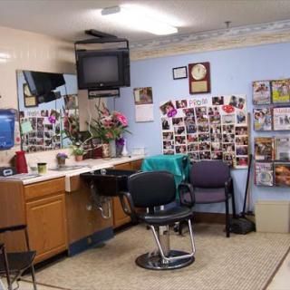 A cozy salon interior featuring a haircut station, comfortable chairs, and a wall adorned with photos.