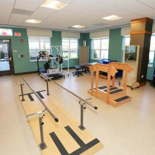 A well-equipped physical therapy room featuring parallel bars and exercise equipment designed for rehabilitation exercises.