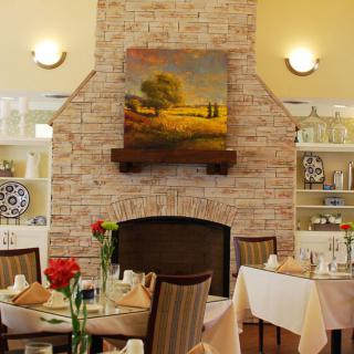 A cozy restaurant dining area featuring a brick fireplace and elegantly set tables.