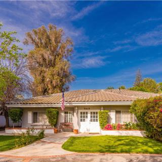 A charming suburban home with a well-maintained yard and clear blue sky.