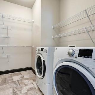 A modern laundry room featuring a washer and dryer with ample shelving space.