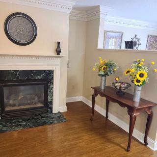 A cozy living room corner with a fireplace and a table adorned with sunflower arrangements.