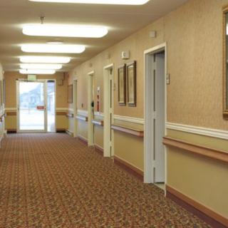 A well-lit hallway with carpeted flooring and multiple doors on either side.