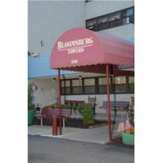 The entrance of a restaurant with a red awning and outdoor seating.