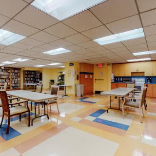 A spacious community room equipped with tables and chairs, designed for gatherings and activities.