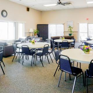 A spacious and well-lit meeting room with round tables and chairs, perfect for gatherings and events.