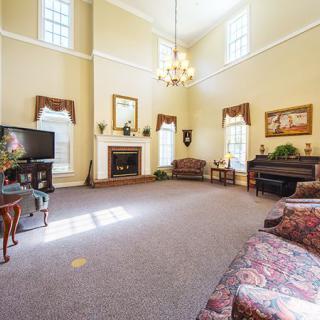 Spacious living room with high ceilings, featuring a chandelier, fireplace, and elegant furniture arrangement.