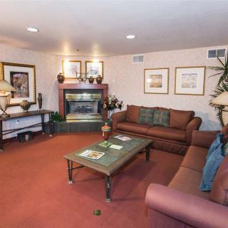 A cozy living room with sofas, a coffee table, artwork on the walls, and a fireplace.