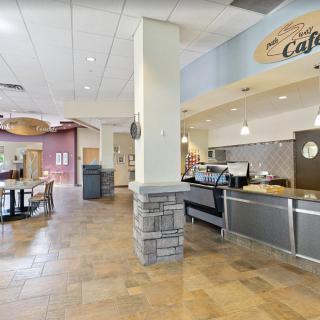 An empty cafe interior with a food service counter and seating area.