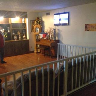 A cozy living room featuring a piano, trophies on display, and a TV.