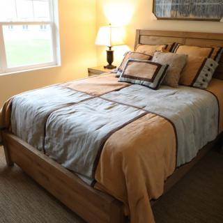 A cozy bedroom with a neatly made bed and warm lighting.