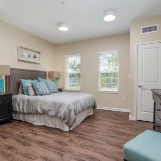 A modern, minimalist bedroom featuring wood flooring and ample natural light.