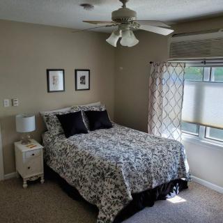 A cozy bedroom with a bed, bedside lamp, and window with curtains.