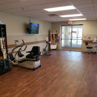 A view of a well-equipped rehabilitation gym with exercise machines and a television.