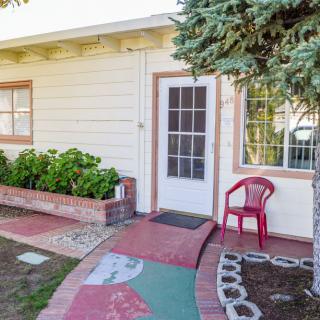 A small house entrance with a pathway, garden, and a red chair.
