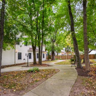 A peaceful pathway lined with trees and a bench, next to a residential building.