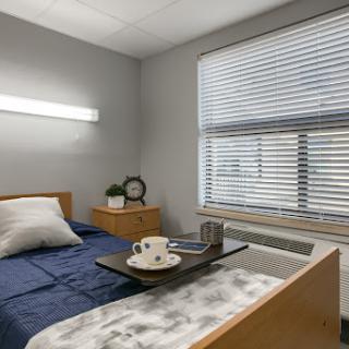 A cozy bedroom with a neatly made bed, a tray with coffee, and natural light streaming through the window.