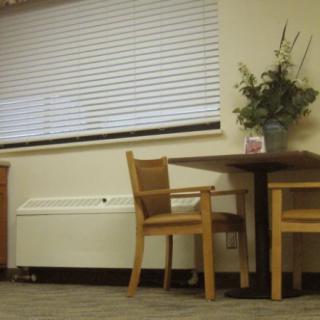 A cozy room corner with a table, chairs, and a window with blinds.