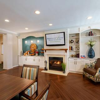A cozy living room featuring a fireplace, built-in shelves, and a dining area with wood flooring.