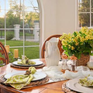 A beautifully set dining table with floral arrangements and a scenic view through the window.