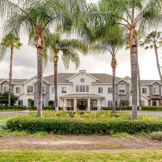 A grand residential building surrounded by palm trees and manicured landscaping.