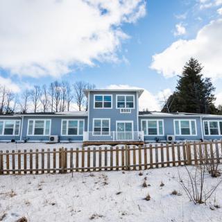 A modern house with a snowy yard and blue skies in the background.
