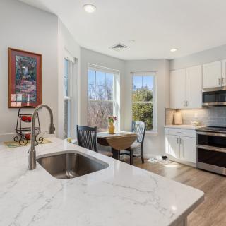 A modern kitchen with a marble countertop, stainless steel appliances, and a cozy dining area by the window.