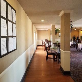 A corridor in a restaurant with tables and chairs lined along one side.