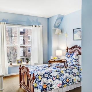 A cozy bedroom with floral bedding and natural light streaming through the window.