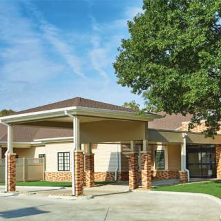 A residential building with a covered entrance and a large tree nearby.