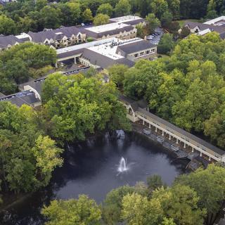 Aerial view of a park with a lake, fountain, and surrounding buildings.