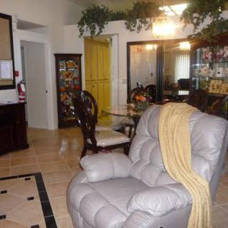 A cozy living room with a recliner and dining area, decorated with plants and warm lighting.
