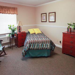 A cozy bedroom with a single bed, dressers, and natural lighting.