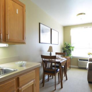 A small apartment kitchen and dining area with a table, chairs, and a window letting in natural light.