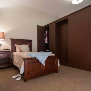 A cozy bedroom featuring a wooden bed and closet with a warm lamp on the bedside table.