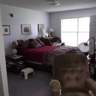 A cozy bedroom with a large bed, lamps on bedside tables, and a window providing natural light.