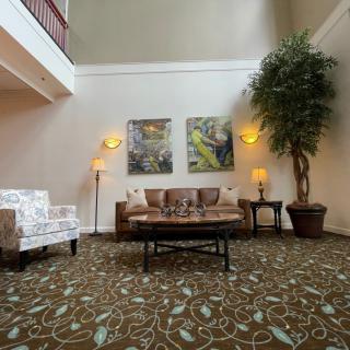 A cozy lobby area featuring a sofa, armchair, and coffee table with warm lighting and decorative artwork.