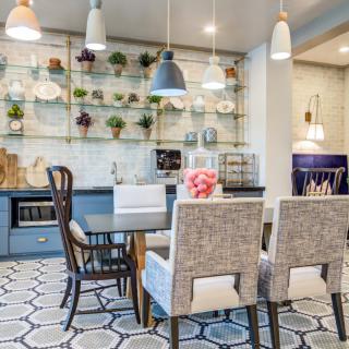 A stylish modern dining room featuring pendant lights, a mix of chairs around a table, and decorative shelving with plants.