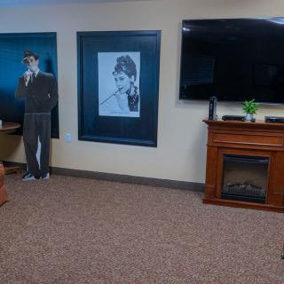 A living room featuring a cardboard cutout, framed photo, television, and fireplace.