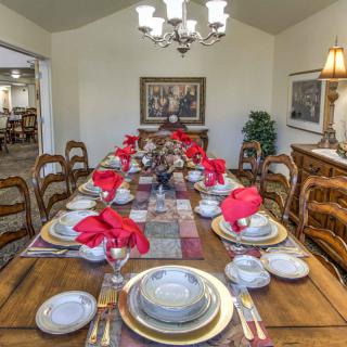 A formal dining room with an elegantly set table adorned with red napkins and stylish dinnerware.