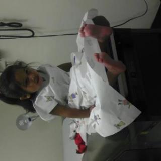 A child sits on an examination table in a doctor's office, wearing a paper gown.