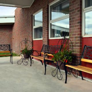 A row of elegantly designed benches with planters, set against a brick wall and large windows.
