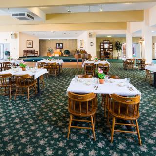 A spacious dining area with neatly arranged tables and chairs, featuring a patterned carpet.